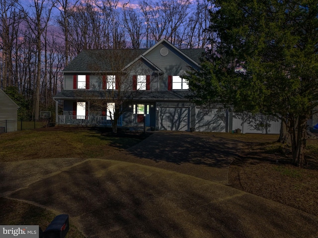 view of front of home featuring a garage, a porch, driveway, and fence