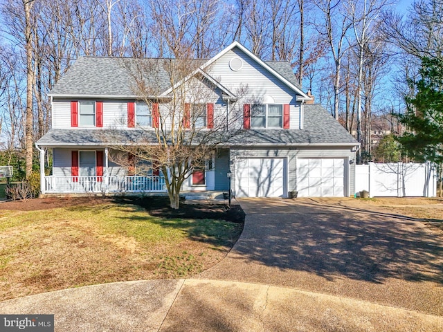 traditional-style house featuring fence, a porch, concrete driveway, a front lawn, and a garage