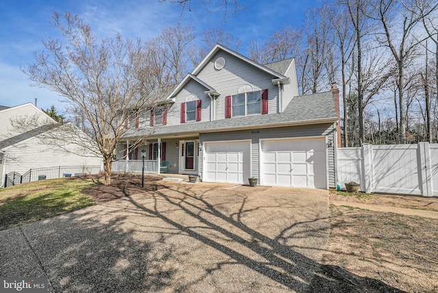 view of front facade with a garage, a porch, driveway, and fence