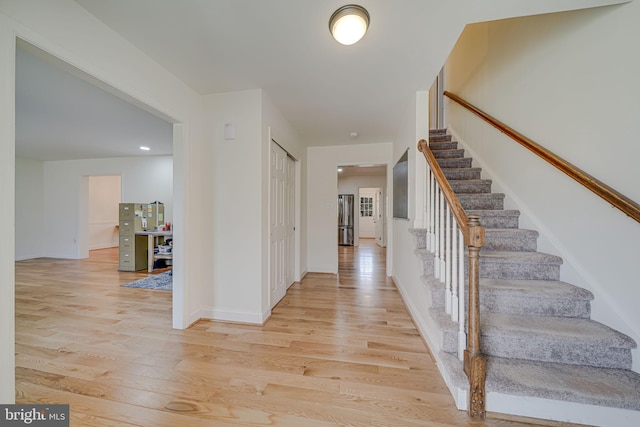 entrance foyer with stairway, baseboards, and light wood-style flooring