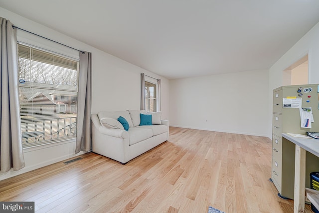 living area featuring light wood finished floors, visible vents, and baseboards