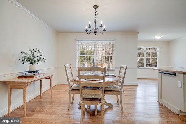 dining space with light wood-style floors, an inviting chandelier, and ornamental molding