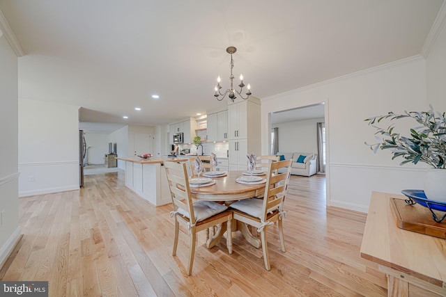 dining space featuring a chandelier, baseboards, light wood-style floors, and ornamental molding