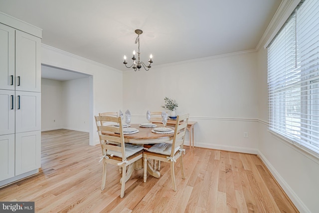 dining room with an inviting chandelier, crown molding, baseboards, and light wood finished floors