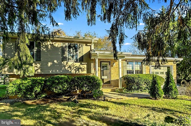 tri-level home featuring a garage, brick siding, and a front yard