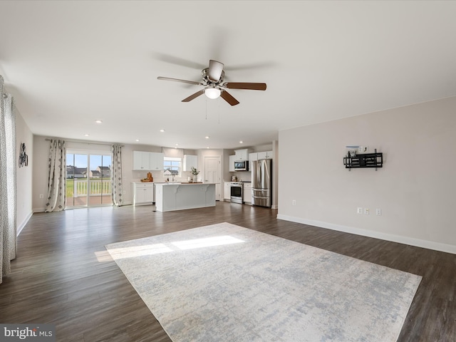 unfurnished living room featuring recessed lighting, baseboards, a ceiling fan, and dark wood finished floors