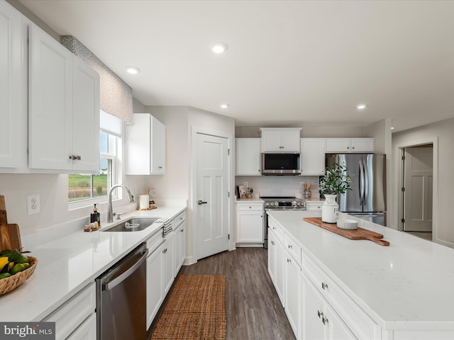 kitchen with white cabinetry, a kitchen island, appliances with stainless steel finishes, a sink, and dark wood-style floors