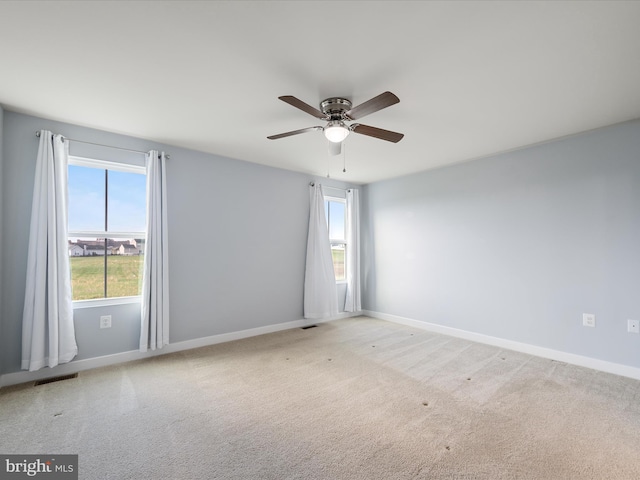 spare room featuring visible vents, baseboards, a ceiling fan, and carpet flooring