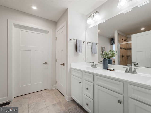 bathroom with a stall shower, double vanity, a sink, and visible vents
