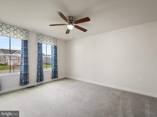 carpeted empty room with visible vents, baseboards, and a ceiling fan