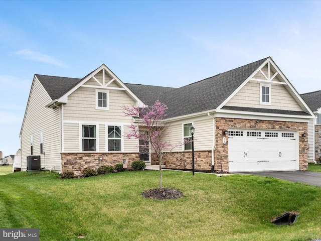 craftsman inspired home featuring a garage, a front yard, cooling unit, and stone siding