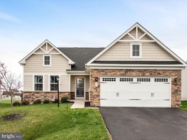 craftsman-style home with stone siding, a front lawn, aphalt driveway, a garage, and a shingled roof