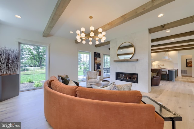 living room featuring recessed lighting, light wood-style floors, a large fireplace, a chandelier, and beamed ceiling