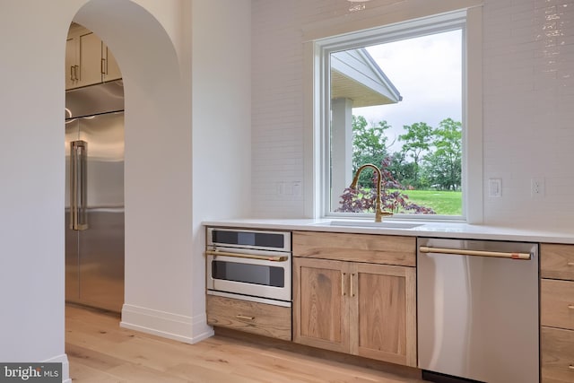 11 Sailfish Dr, Mechanicsburg, PA 17050 - kitchen featuring appliances with stainless steel finishes, light wood-style flooring, light countertops, light brown cabinetry, and arched walkways