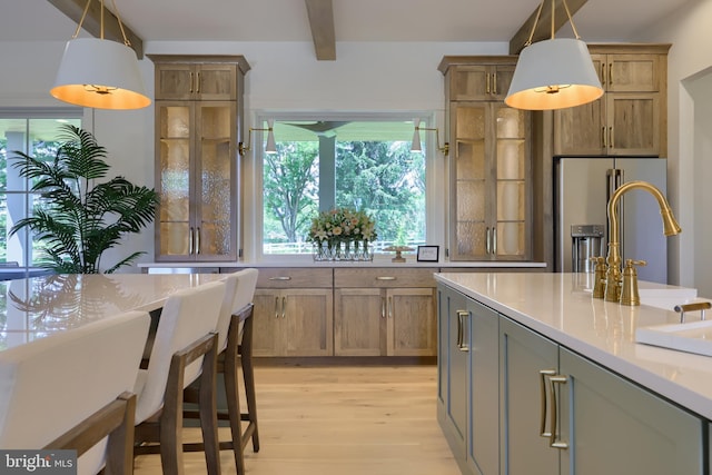 kitchen featuring light wood-style flooring, stainless steel refrigerator with ice dispenser, beam ceiling, and decorative light fixtures