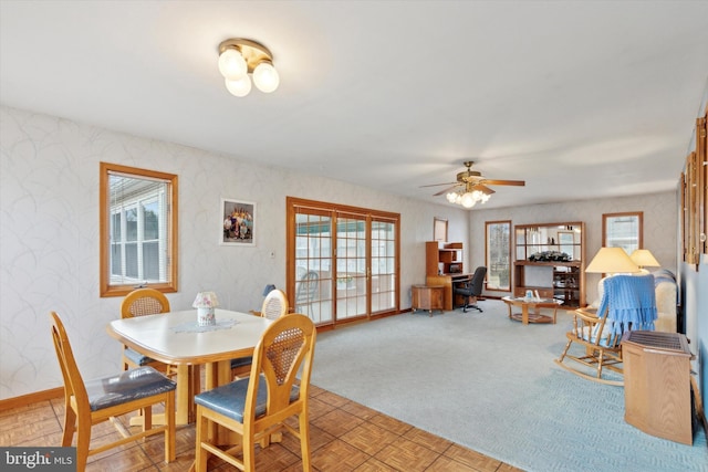 carpeted dining area featuring a ceiling fan, baseboards, and wallpapered walls