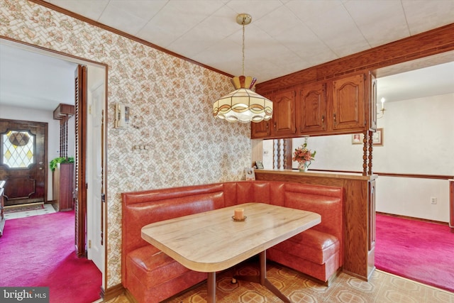 carpeted dining area with baseboards, ornamental molding, breakfast area, and wallpapered walls