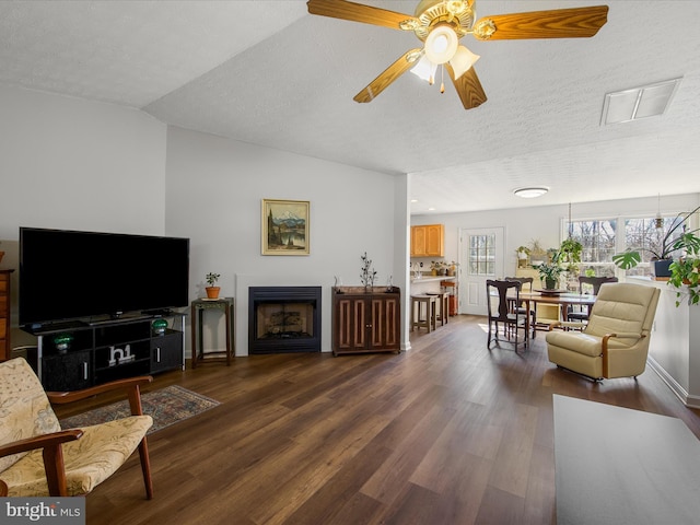 living room with a textured ceiling, dark wood-style flooring, a fireplace, and vaulted ceiling