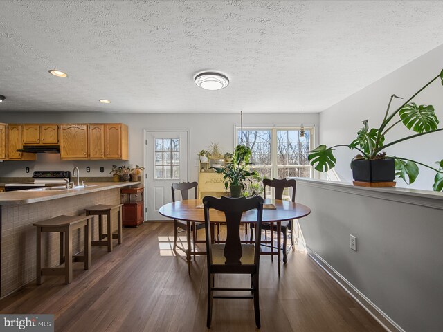 dining space featuring recessed lighting, dark wood-style flooring, a textured ceiling, and baseboards