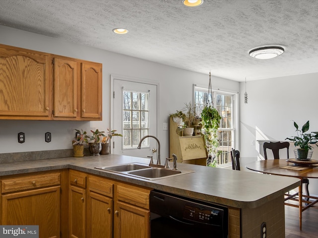 kitchen featuring brown cabinets, dishwasher, a peninsula, and a sink