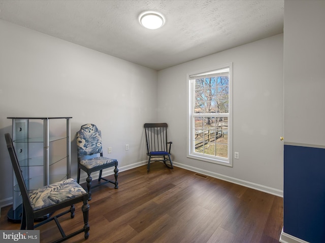 sitting room featuring dark wood-style floors, visible vents, a textured ceiling, and baseboards