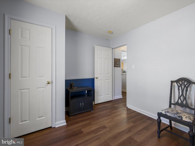 living area featuring dark wood-style floors, a textured ceiling, and baseboards