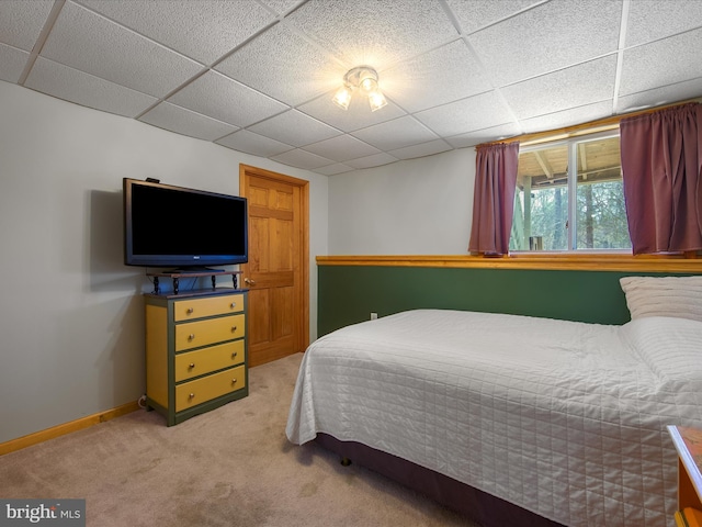 bedroom featuring light colored carpet, a drop ceiling, and baseboards