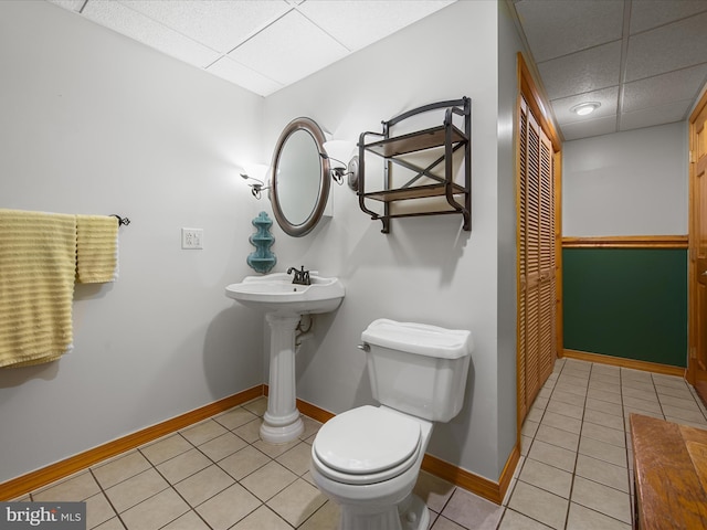 bathroom with a paneled ceiling, baseboards, toilet, and tile patterned floors