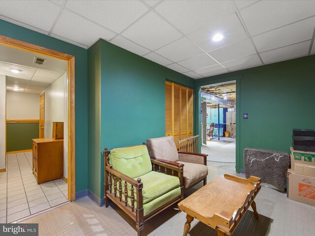 sitting room featuring a paneled ceiling, light tile patterned floors, baseboards, and visible vents