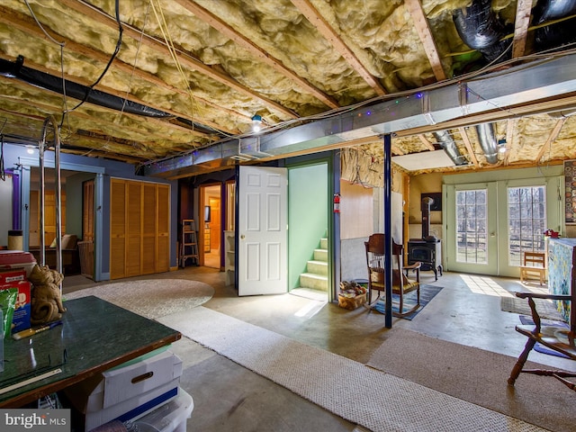 below grade area with a wood stove, stairs, and french doors