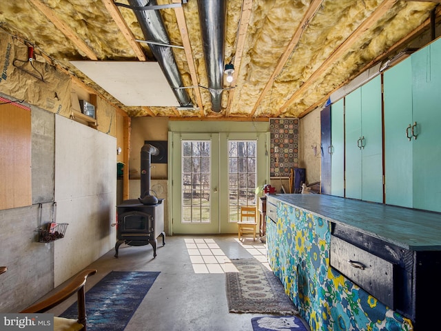 interior space featuring a wood stove, french doors, and unfinished concrete floors