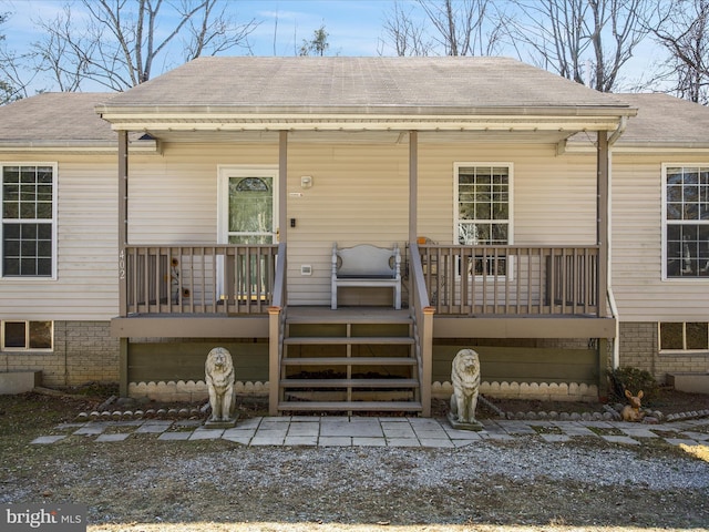 rear view of property with a porch and roof with shingles