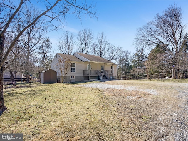 back of property featuring a yard, fence, an outdoor structure, and a storage unit