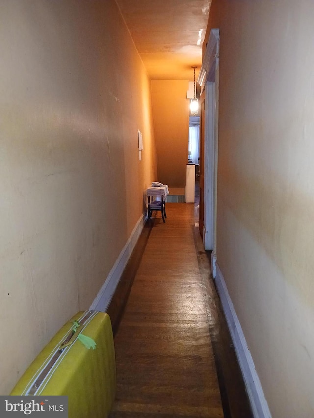 corridor featuring wood finished floors and baseboards