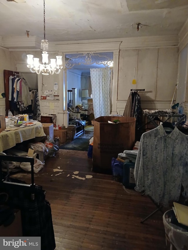 interior space featuring ornamental molding, a decorative wall, wood finished floors, and a chandelier