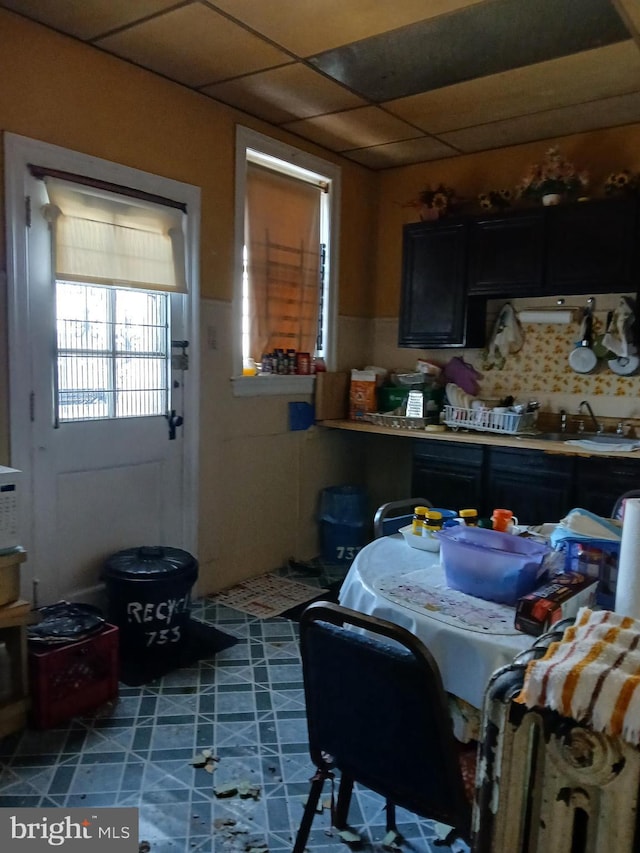 kitchen with a paneled ceiling, decorative backsplash, a sink, and tile patterned floors