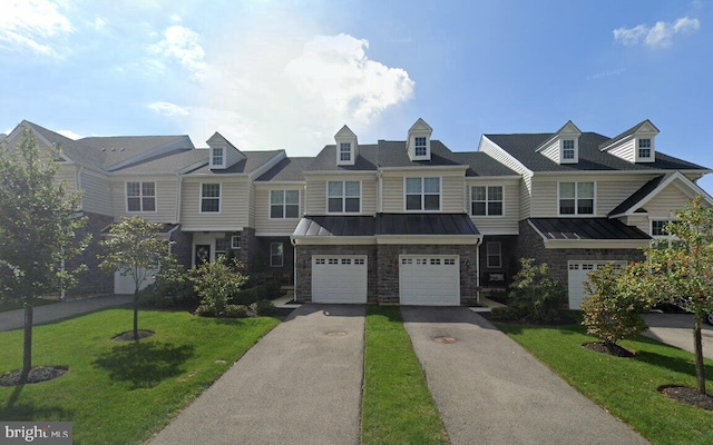 townhome / multi-family property with a front yard, a standing seam roof, a garage, stone siding, and driveway