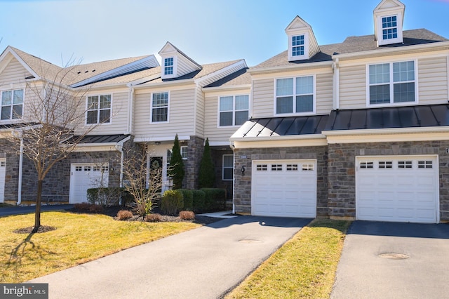 view of property with aphalt driveway, a standing seam roof, metal roof, and an attached garage