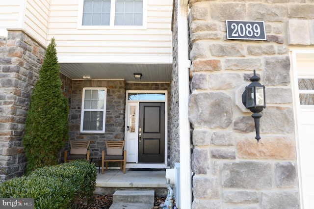 entrance to property with stone siding and a porch