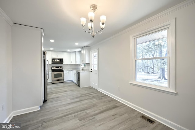 kitchen featuring crown molding, stainless steel appliances, light countertops, visible vents, and a sink