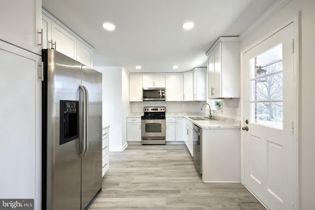 kitchen featuring tasteful backsplash, recessed lighting, appliances with stainless steel finishes, light wood-style floors, and a sink