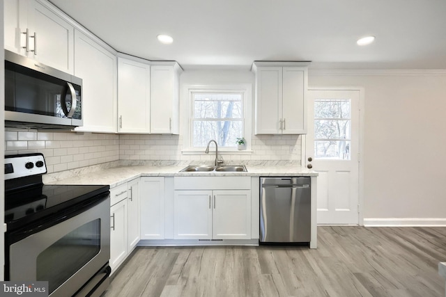 kitchen featuring light wood-type flooring, white cabinetry, appliances with stainless steel finishes, and a sink