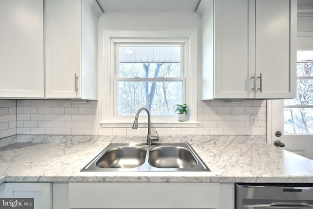 kitchen featuring dishwasher, white cabinets, a sink, and decorative backsplash