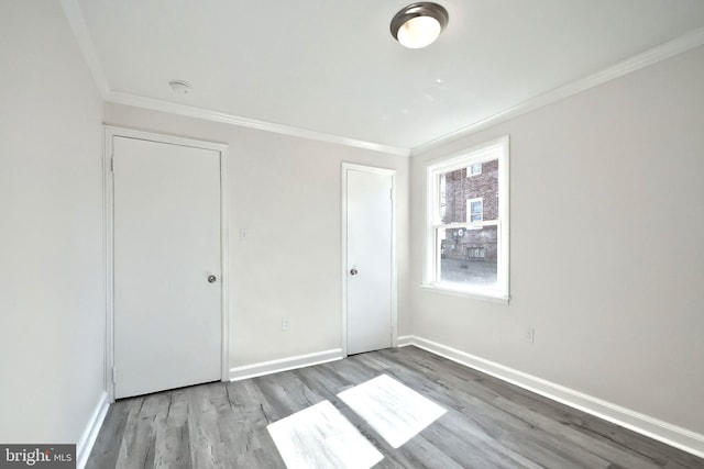 unfurnished bedroom featuring baseboards, ornamental molding, and wood finished floors