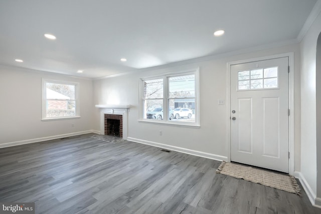 entrance foyer featuring ornamental molding, a fireplace, baseboards, and wood finished floors