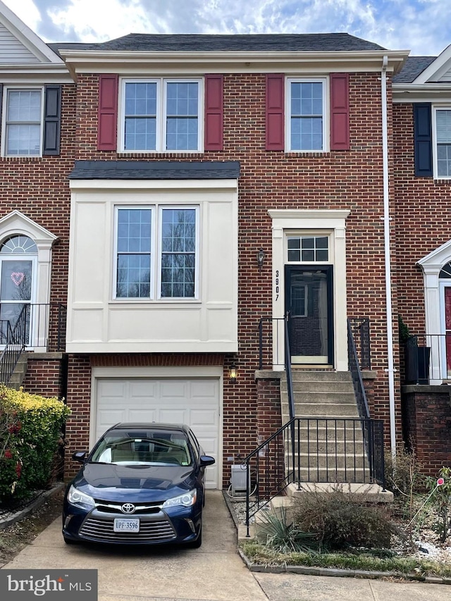 townhome / multi-family property with an attached garage, concrete driveway, and brick siding