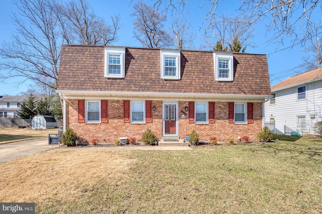 view of front of home featuring a shingled roof, mansard roof, and brick siding