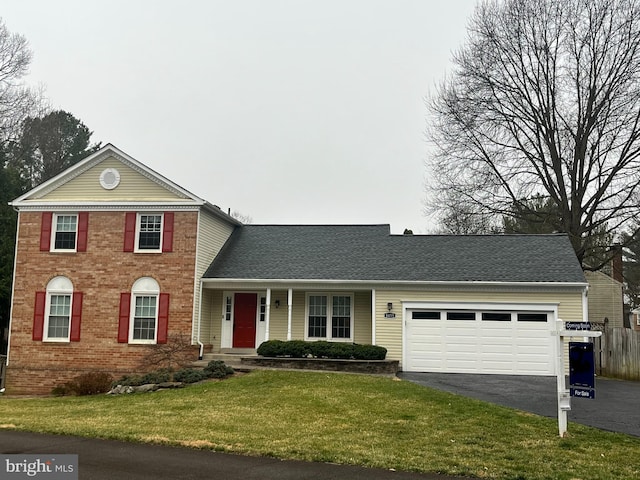 traditional-style home with a shingled roof, a front lawn, a garage, aphalt driveway, and brick siding