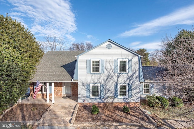 view of front of home with brick siding and roof with shingles