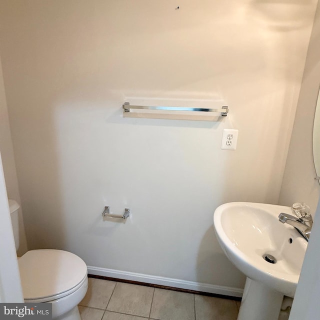 bathroom featuring toilet, tile patterned flooring, baseboards, and a sink